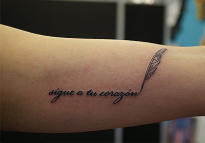 スペイン語「sigue a tu corazón」の文字のタトゥー