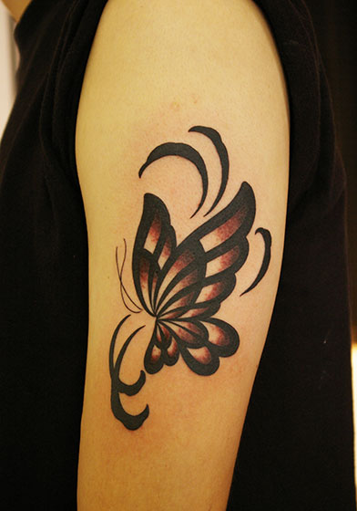 LUCKY ROUND TATTOOの女性の上腕への黒い蝶のタトゥー