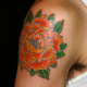 オレンジ色の牡丹の右側のタトゥー