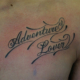 筆記体「Adventure Lover」のタトゥー