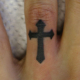 指の十字架のカバーアップのタトゥー