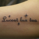 筆記体のラテン語「Luceat lux tua」のタトゥー